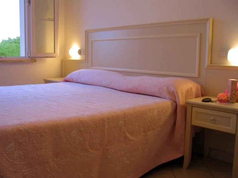 Camera da letto con letto matrimoniale e copriletto rosa.