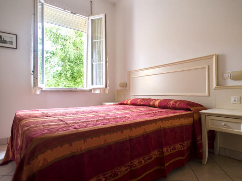 Camera da letto luminosa con finestra aperta e letto matrimoniale.