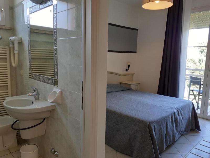Camera semplice con bagno, balcone e letto matrimoniale.