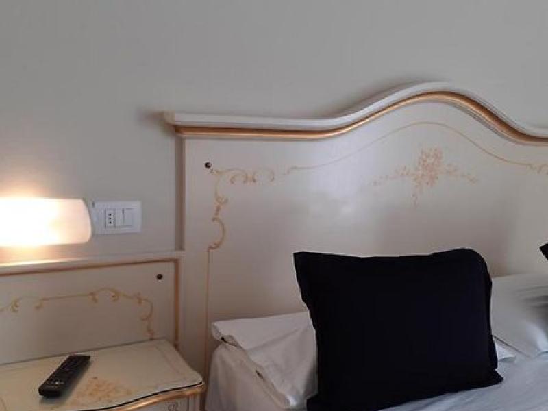 Camera elegante con letto, cuscino nero e comodino.