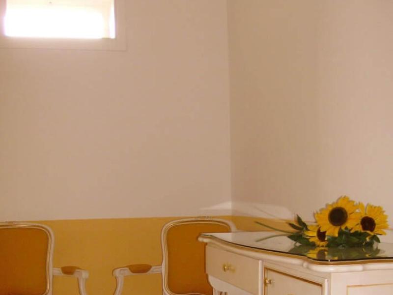 Stanza elegante con sedie gialle e girasoli su un mobile.