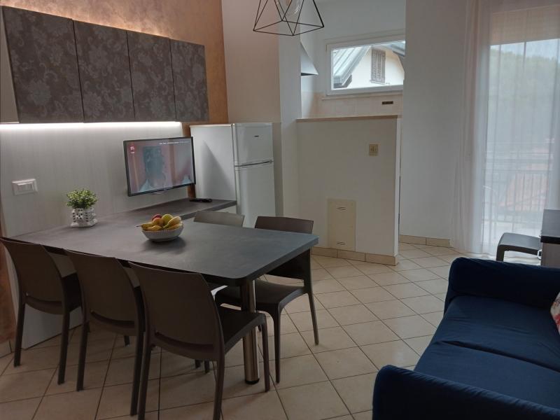 Moderno soggiorno con cucina, tavolo, TV e divano.