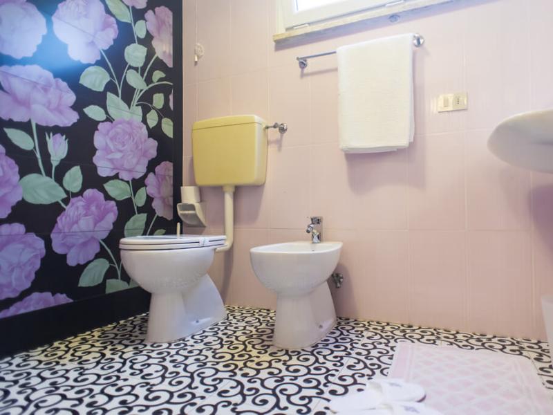 Bagno con carta da parati floreale e piastrelle decorative.