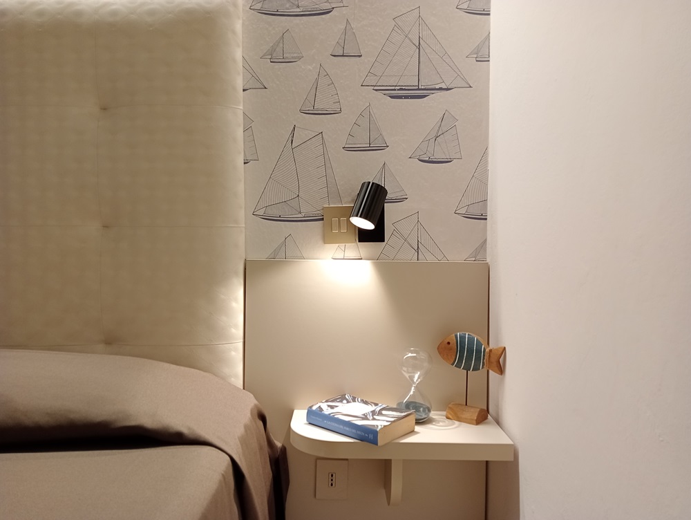 Camera con decorazioni nautiche, lampada, clessidra e libro.